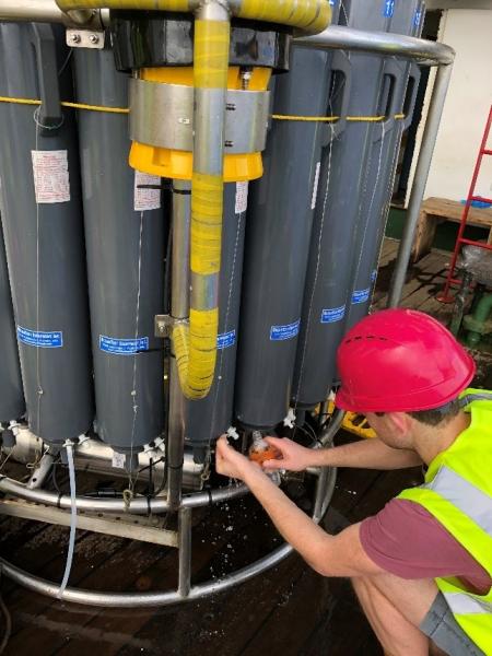 Thomas Wilder sampling water from the CTD for salinity analysis.