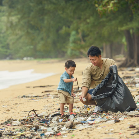 Image of a father and young son on a beach collecting plastic rubbish